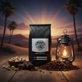 Coffee bag with 'Evil's Lantern Coffee Co.' branding on a wooden surface with coffee beans, chocolate, and nuts, set against a desert sunset.